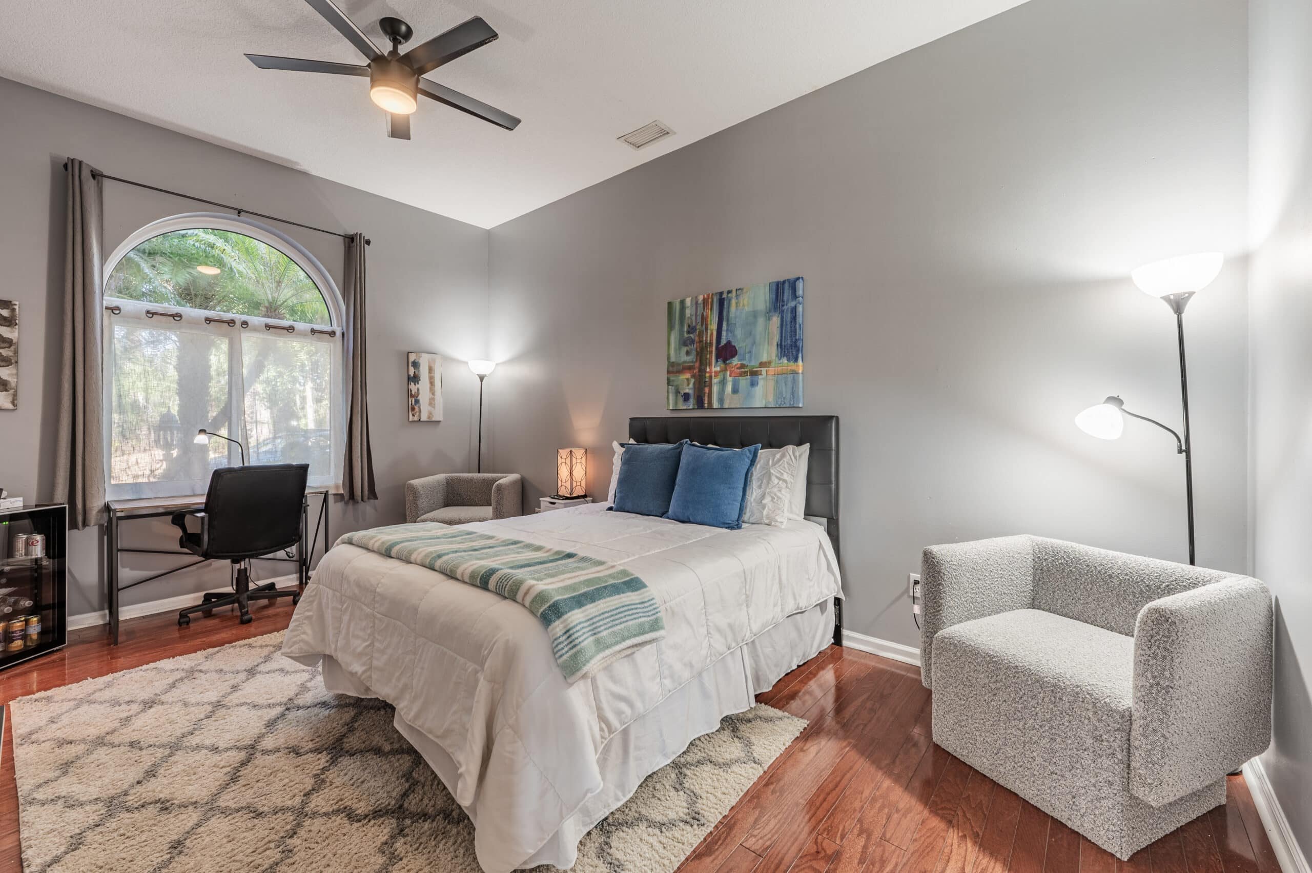 A guest bedroom at Tikvah Lake Recovery, morning light through an arched window